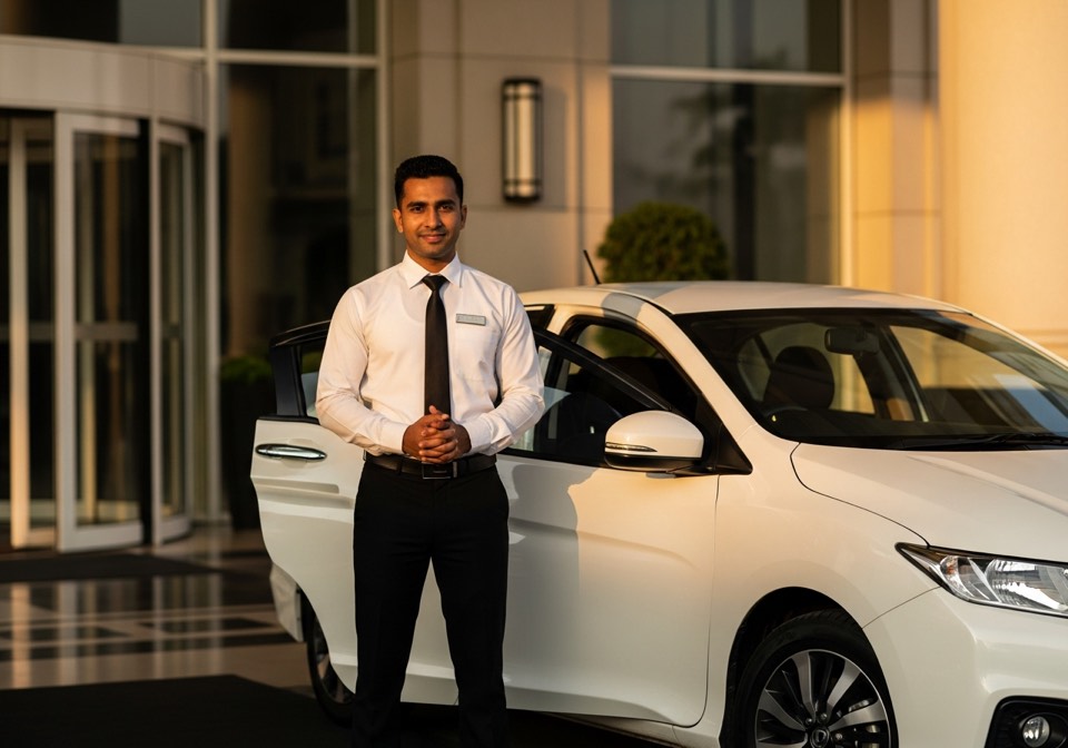 A DriverOnDoor chauffeur in uniform standing beside a customer's car